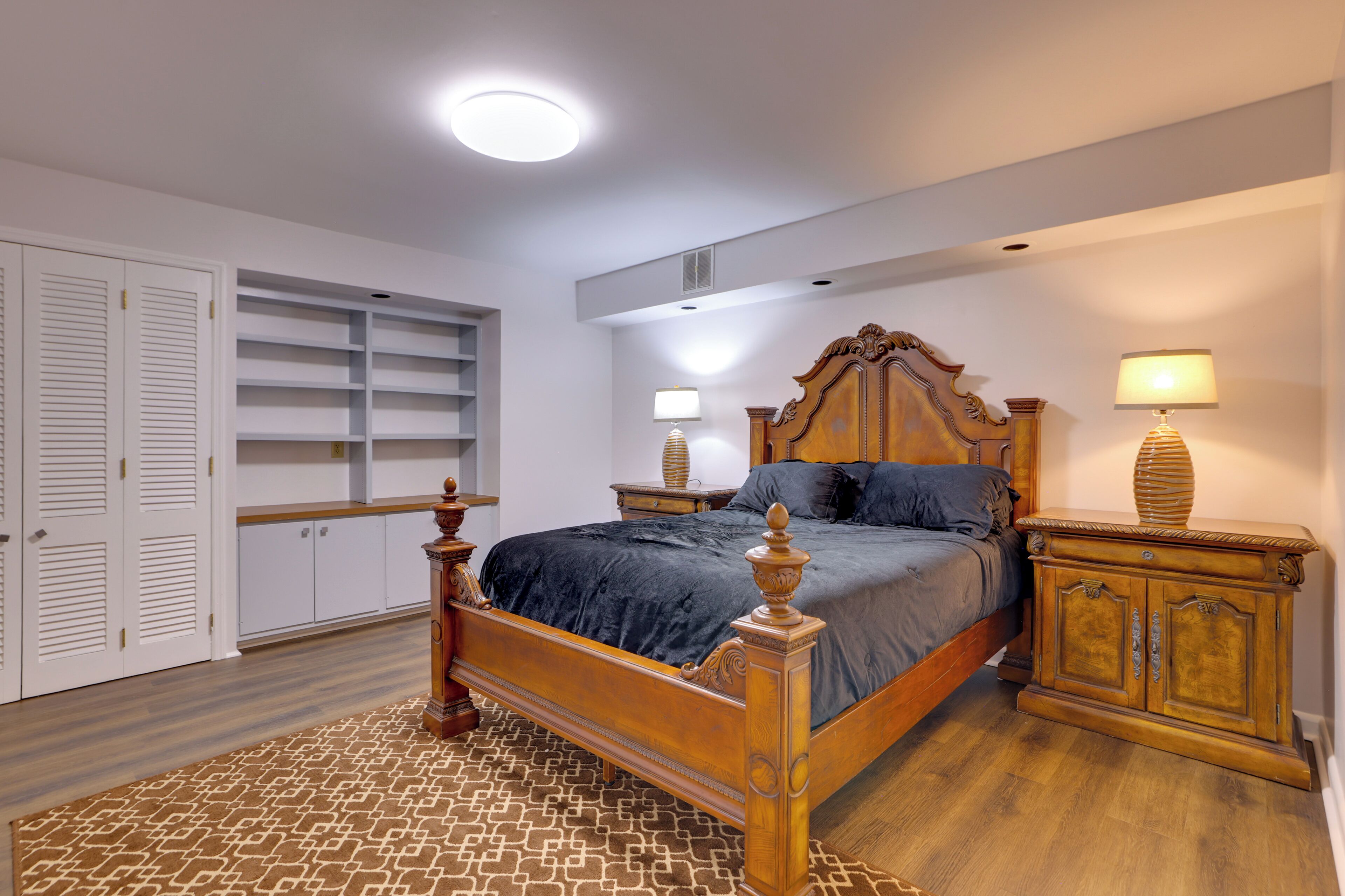 A bedroom with a wooden bed, white closet, and built-in shelves.
