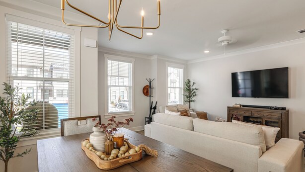 A modern living room with a wooden dining table, a sofa, and a flat-screen TV. - King Suites for Every Couple, Kickoff 3 Mi (Oxford)