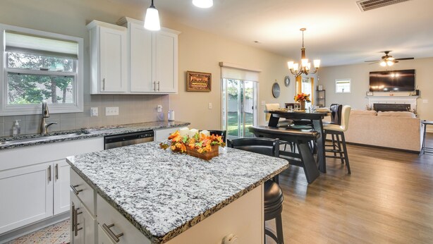 Eine moderne Küche mit Granit Arbeitsplatten, weißen Schränken und einem Essbereich mit einer Chandelier.