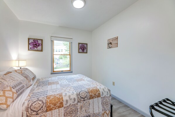 Un dormitorio con una cama grande, una ventana y dos cuadros colgados en la pared.