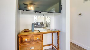 Un escritorio de madera con un televisor de pantalla plana montado encima, un espejo y un pequeño objeto decorativo sobre la mesa.