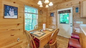 A wooden cabin interior with a dining table, chairs, a chandelier, and a framed picture of a wolf. - 3 Mi to Dale Hollow Lake: Wooded Retreat w/ Decks! (Byrdstown)