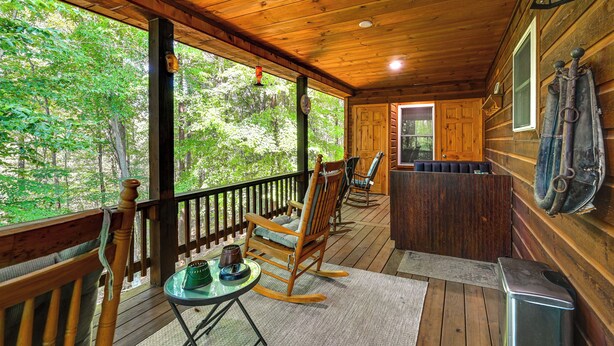 A wooden cabin with a porch, rocking chairs, a table, and a view of the forest. - 3 Mi to Dale Hollow Lake: Wooded Retreat w/ Decks! (Byrdstown)