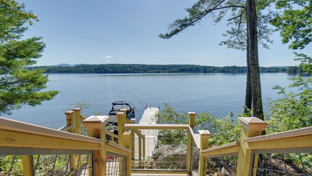 A wooden deck leading to a lake with a boat docked on the right. - Walk to Lake Winnisquam Access: Cozy Retreat (Sanbornton)