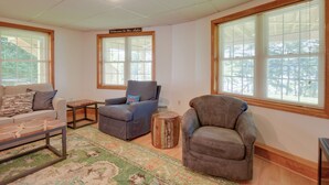 A living room with a sofa, two armchairs, a coffee table, and a rug. There are large windows with blinds and a sign that reads "Welcome to the lake." - Walk to Lake Winnisquam Access: Cozy Retreat (Sanbornton)