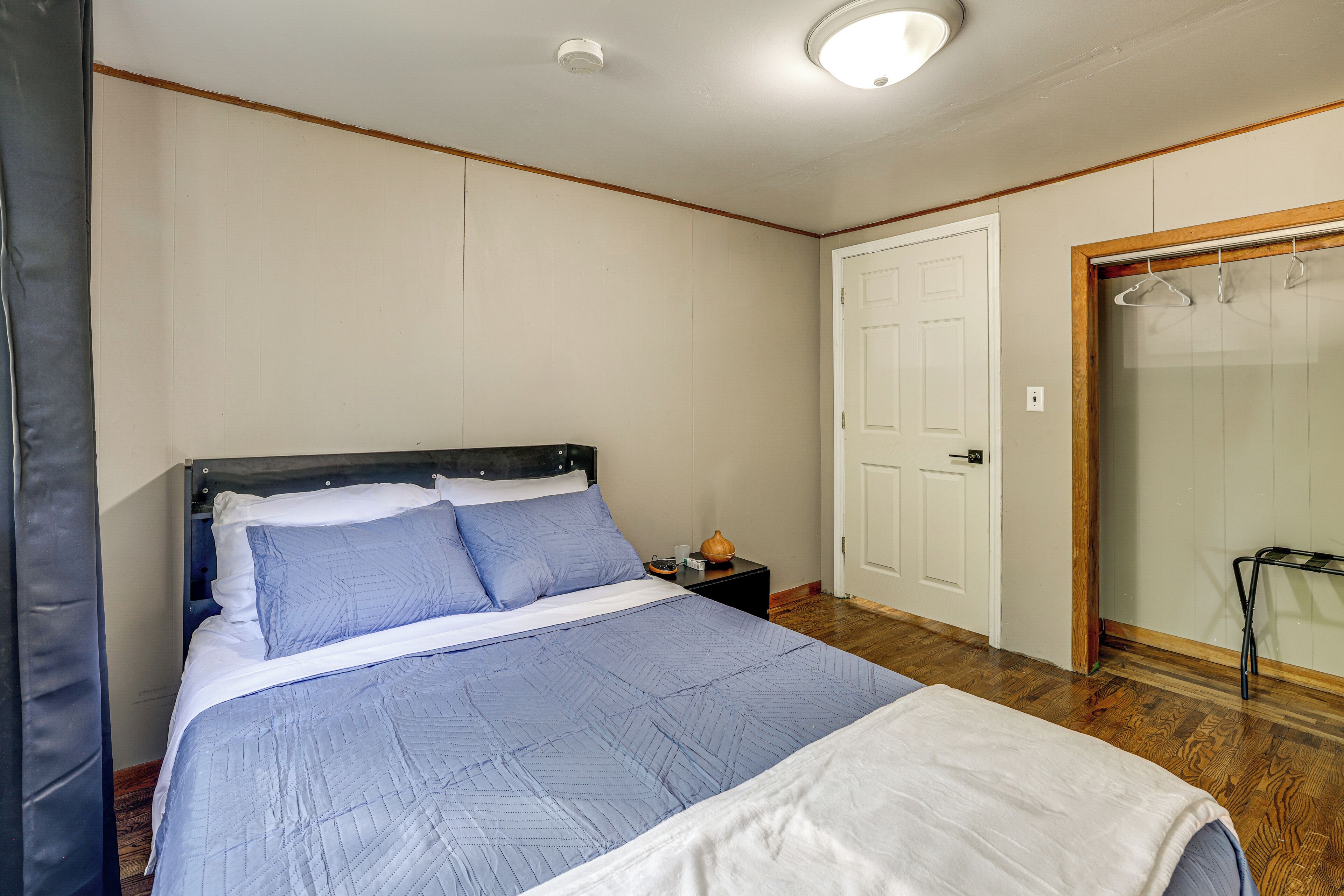 A bedroom with a bed, a nightstand, a door, and a closet.