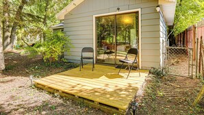 Une petite terrasse en bois avec deux chaises et une porte vitrée donnant sur un espace abrité.