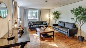 Un salon moderne avec un canapé d’angle, une table basse et deux plantes en pot.
