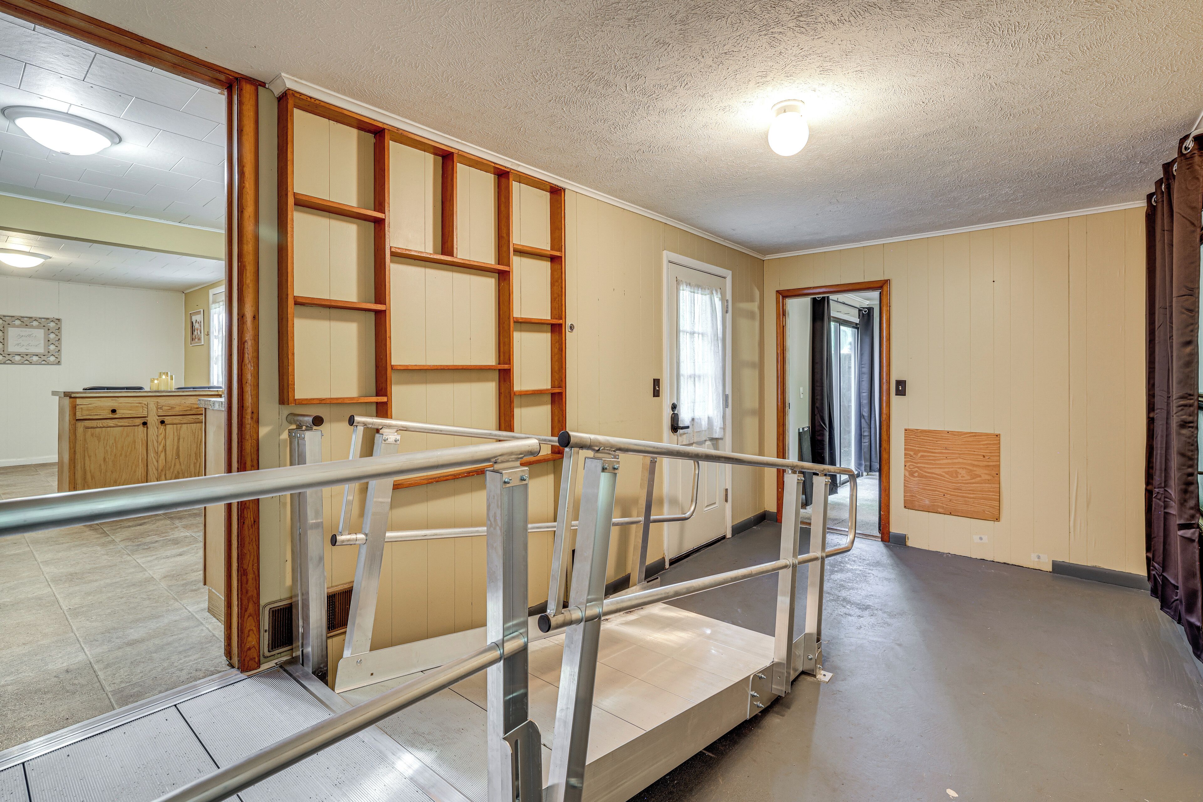 A hallway with a metal handrail, wooden paneling, and a door leading to another room.