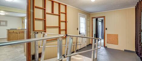 A hallway with a metal handrail, wooden paneling, and a door leading to another room.