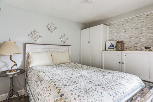 A bedroom with a bed, a nightstand, a lamp, and a wardrobe. - Steps to Short Beach: Ocean-view Apt w/ Deck! (Winthrop)