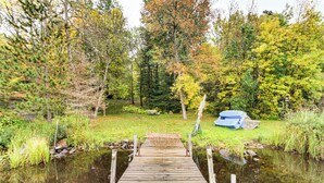 A wooden dock leading into a pond surrounded by trees with autumn foliage. - Sauna + Deck: Wooded Cabin on Lake Vermilion! (Tower)