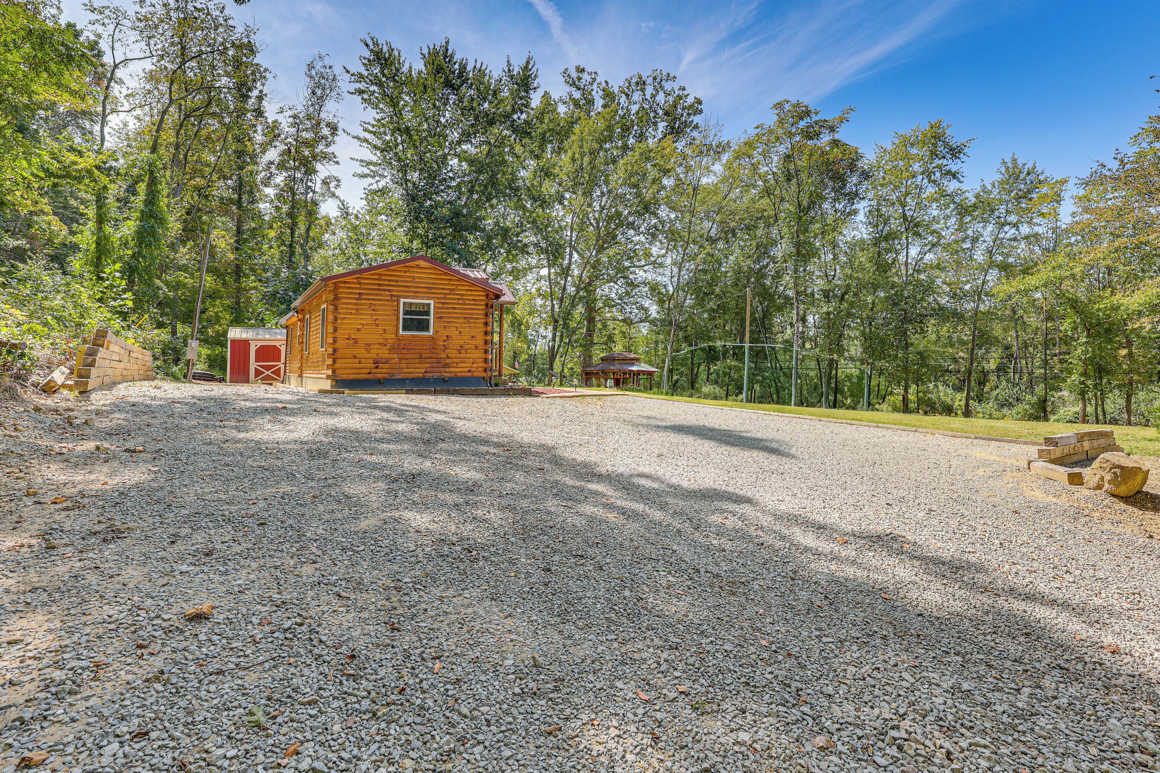 Une cabane en bois avec une allée en gravier, entourée d’arbres.