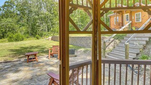 A wooden gazebo with a view of a wooden cabin and a stone patio area with outdoor seating.