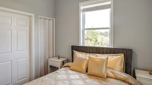 Une chambre à coucher avec un lit, une table de chevet, une fenêtre et une porte.
