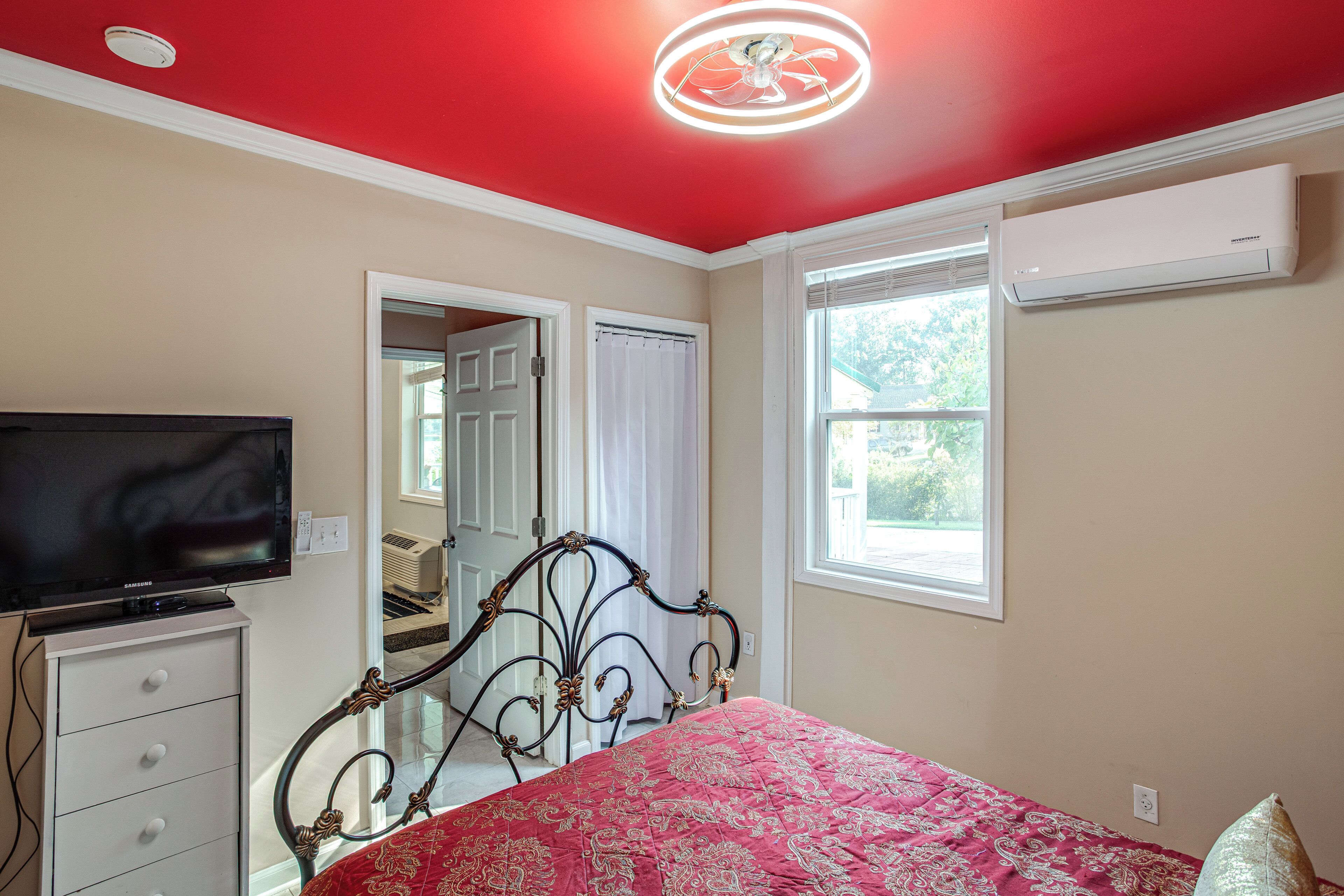 Un dormitorio con cama, televisión, cómoda y ventana.