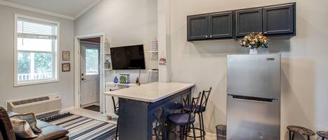 A modern kitchen with a built-in island, dark cabinets, and a stainless steel refrigerator.