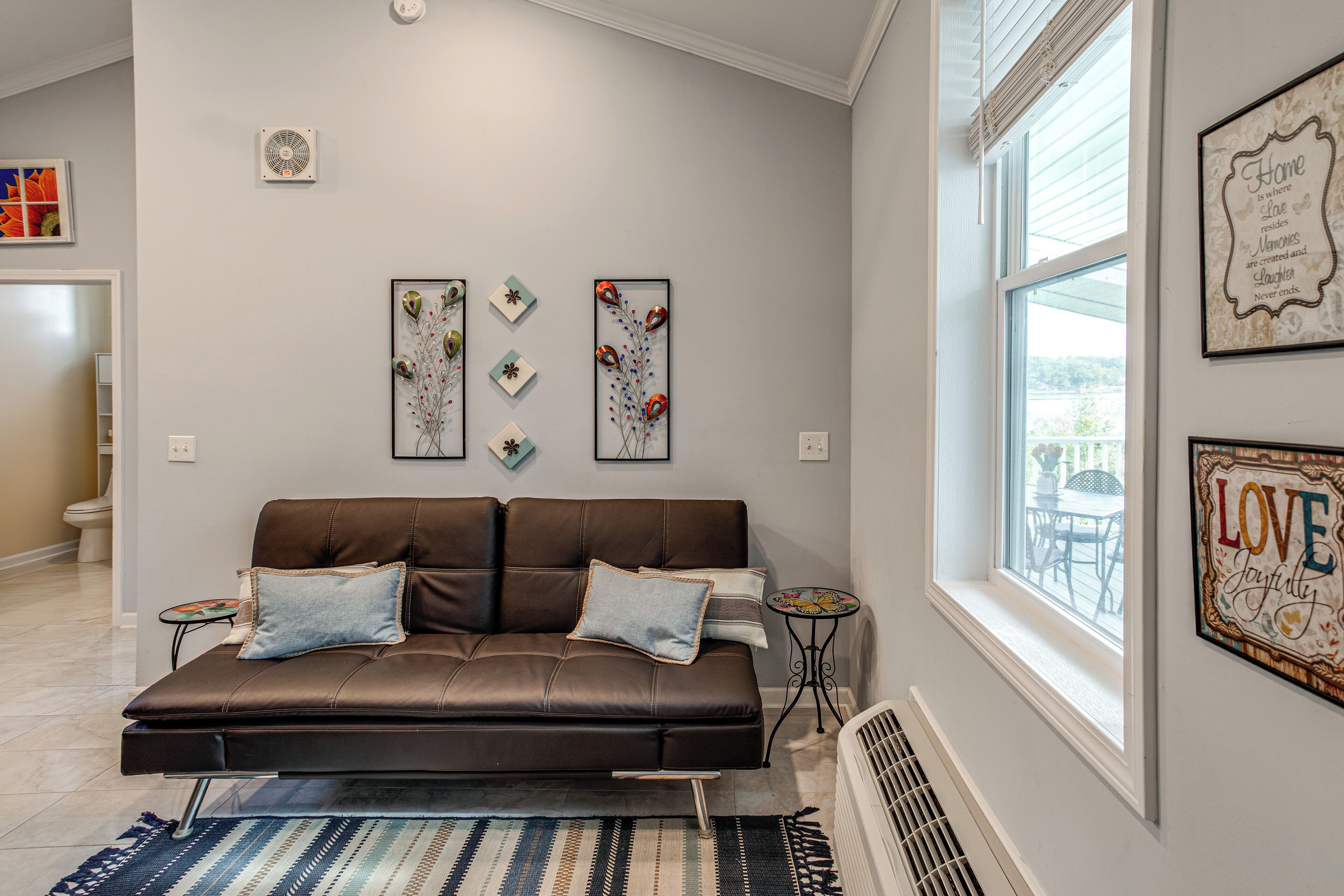 A modern living room with a brown leather sofa, a small side table, and decorative wall art.