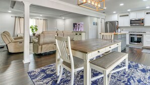 A modern kitchen with white cabinets, stainless steel appliances, and a wooden dining table with chairs. - Fenced Yard: Home < 1 Mi to Mayor Pablo Peña Park (Weslaco)