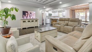 A spacious living room with a large beige sofa, a coffee table, and a television on the wall. - Fenced Yard: Home < 1 Mi to Mayor Pablo Peña Park (Weslaco)