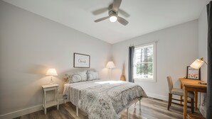 A bedroom with a bed, bedside tables, a desk, and a chair.