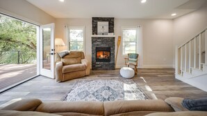 A spacious living room with a stone fireplace, a large sofa, and a view of the outdoors.