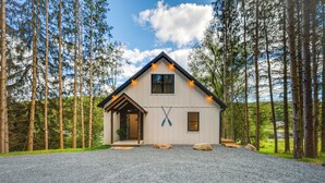 A house with a sloped roof, a front porch, and a gravel driveway.