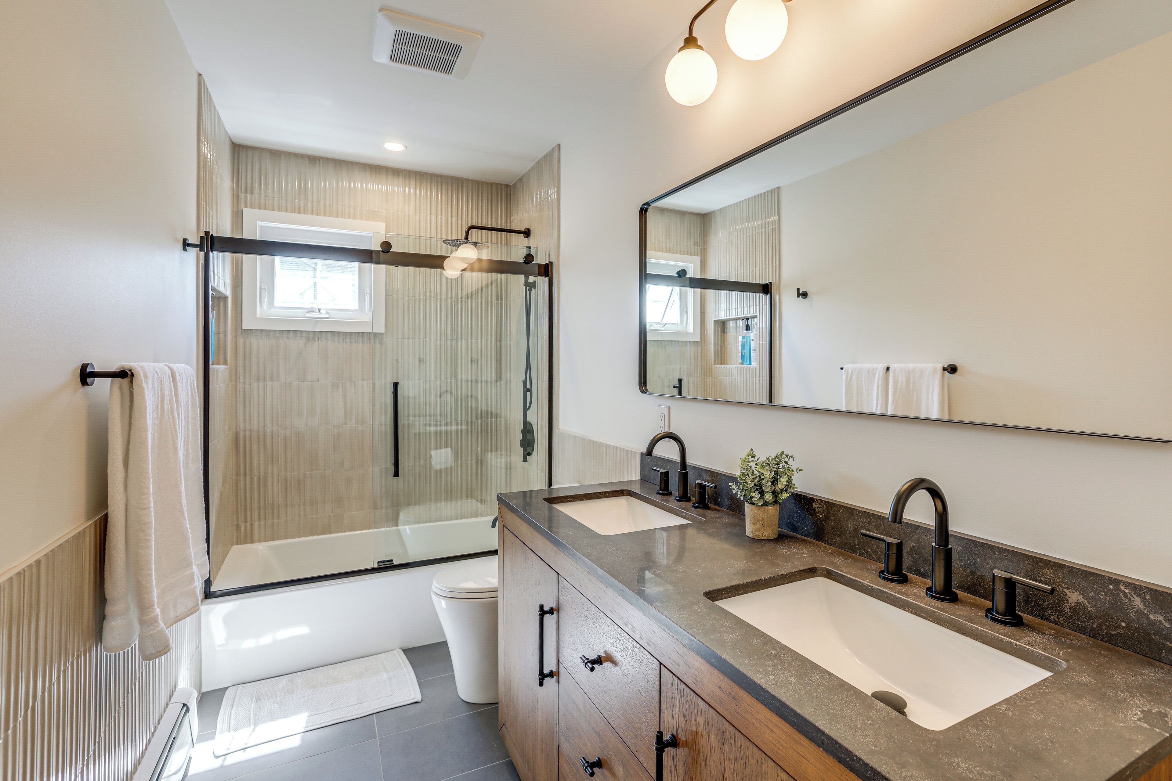 A modern bathroom with a glass shower enclosure, two sinks, and a large mirror.