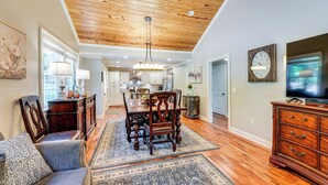 A spacious living room with a wooden ceiling, a dining area with a chandelier, and a television on a wooden cabinet. - Peaceful Home w/ Porch & Yard, 5 Mi to Rome! (Rome)