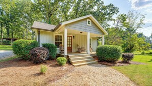 A small, single-story house with a porch, surrounded by well-maintained bushes and a gravel driveway. - Peaceful Home w/ Porch & Yard, 5 Mi to Rome! (Rome)