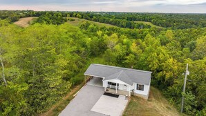 A single-story house with a covered porch, surrounded by dense forest and rolling hills. - Kentucky Countryside Escape: 5 Mi to Williamstown! (Williamstown)