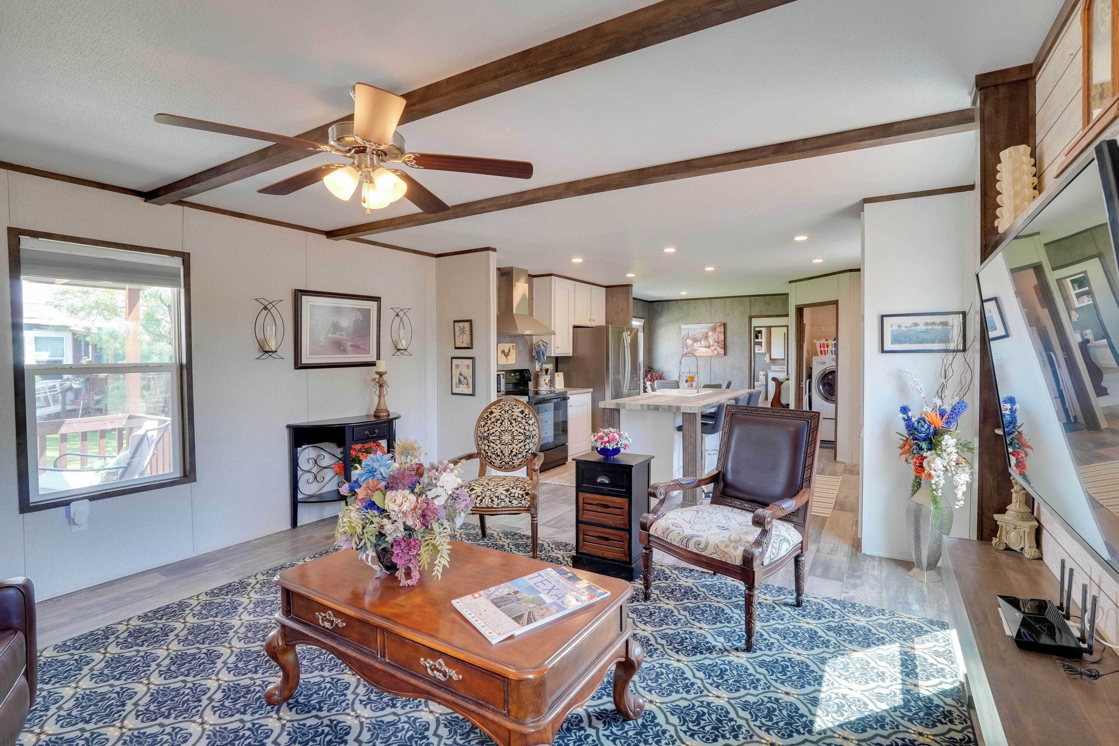 A spacious living room with a ceiling fan, a wooden coffee table, and a large window.
