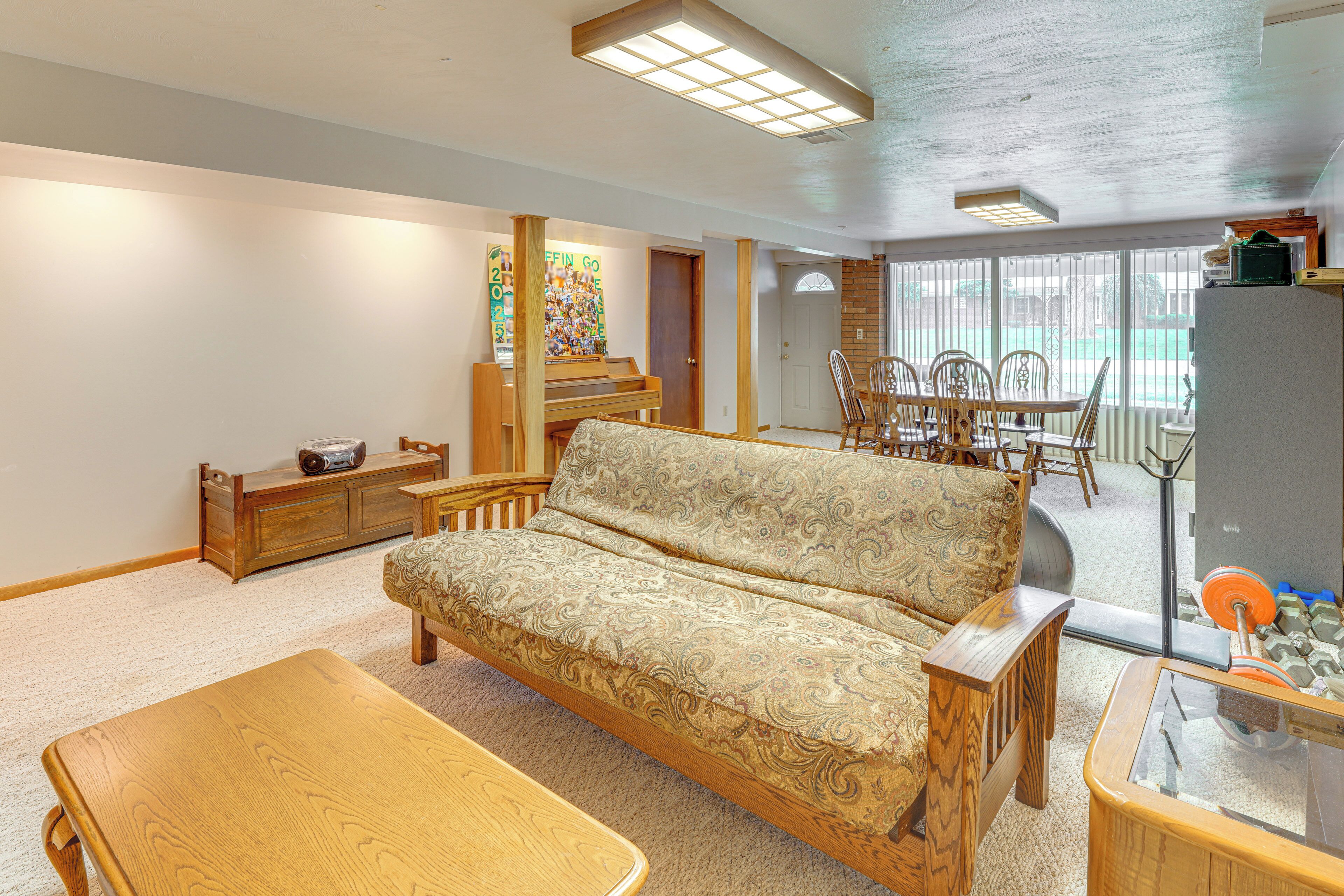 Ein Wohnzimmer mit einer Couch, einem Holztisch, einem Klavier und einem Essbereich mit Stühlen.