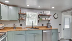 A kitchen with light green cabinets, a wooden countertop, a sink, a dishwasher, and a window with blinds. - Fish, Hike & Golf: Leisurely Navarre Home w/ Yard! (Navarre)