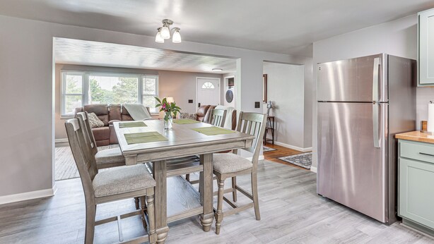 A modern kitchen with a stainless steel refrigerator, wooden dining table, and chairs. - Fish, Hike & Golf: Leisurely Navarre Home w/ Yard! (Navarre)