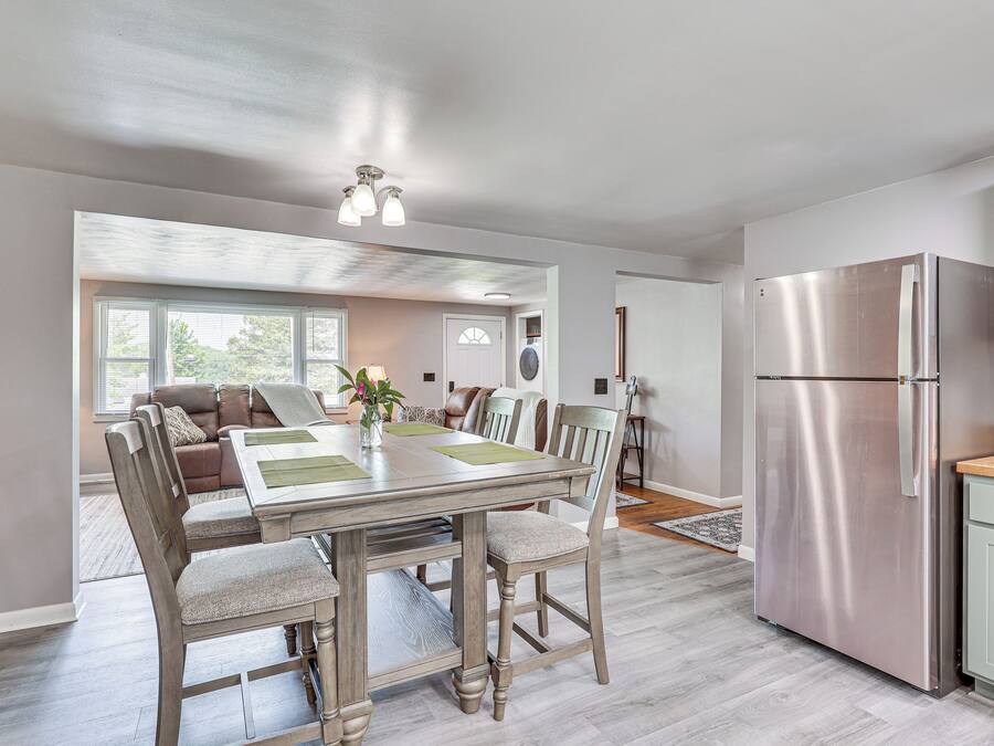 A modern kitchen with a stainless steel refrigerator, wooden dining table, and chairs.