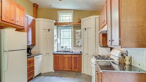 A kitchen with wooden cabinets, a refrigerator, a stove, and a window. - Cottage By the Pond: Serene Northeast Ohio Retreat (Paris)