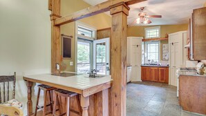 A kitchen with a wooden island, bar stools, and a ceiling fan. - Cottage By the Pond: Serene Northeast Ohio Retreat (Paris)