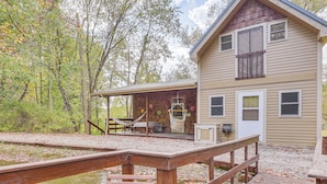 A wooden house with a porch, a swing, and a dock extending into a body of water. - Cottage By the Pond: Serene Northeast Ohio Retreat (Paris)