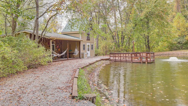 A rustic cabin with a porch and a dock extending into a pond. - Cottage By the Pond: Serene Northeast Ohio Retreat (Paris)