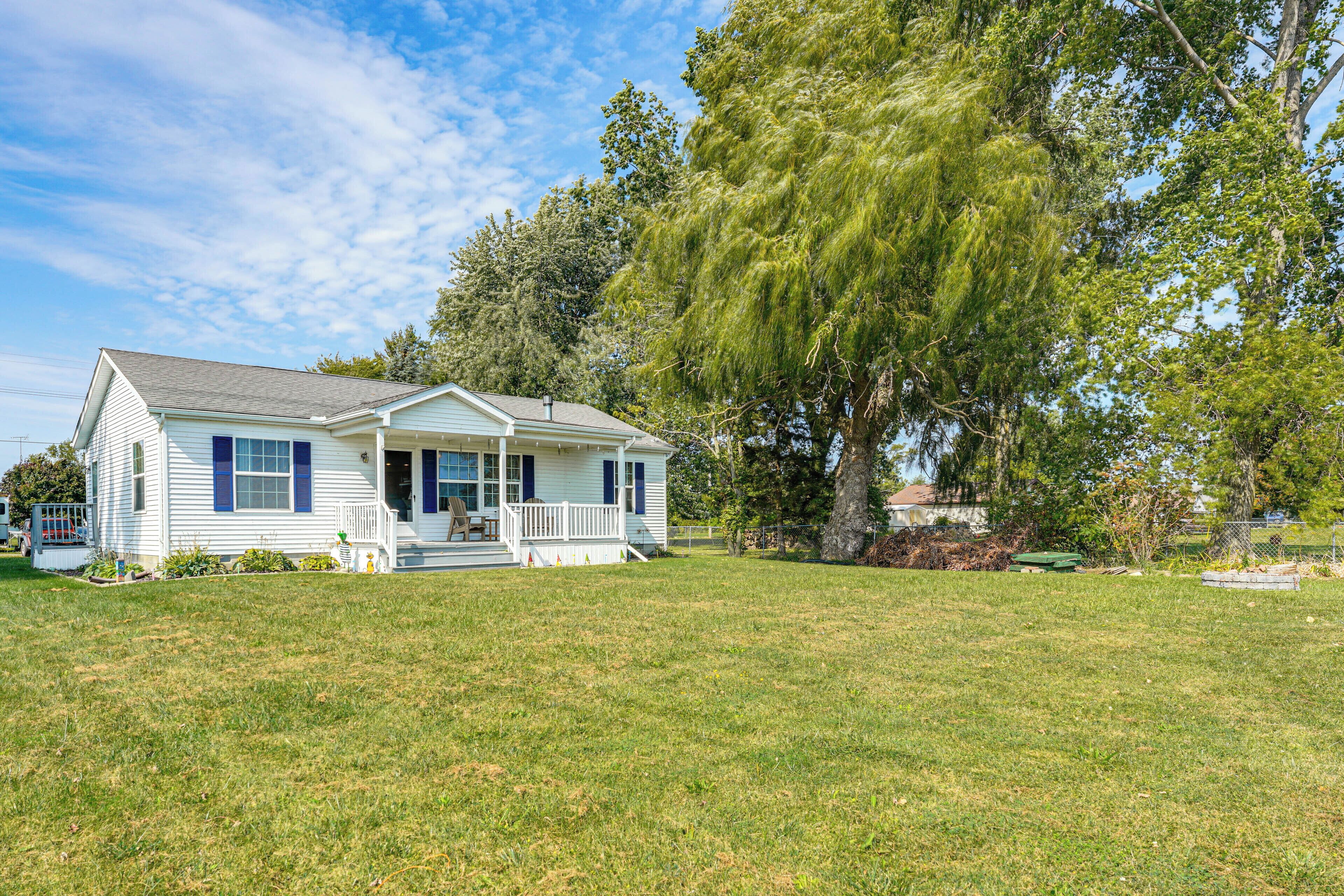 A single-story house with a front porch, surrounded by a well-maintained lawn and large trees.