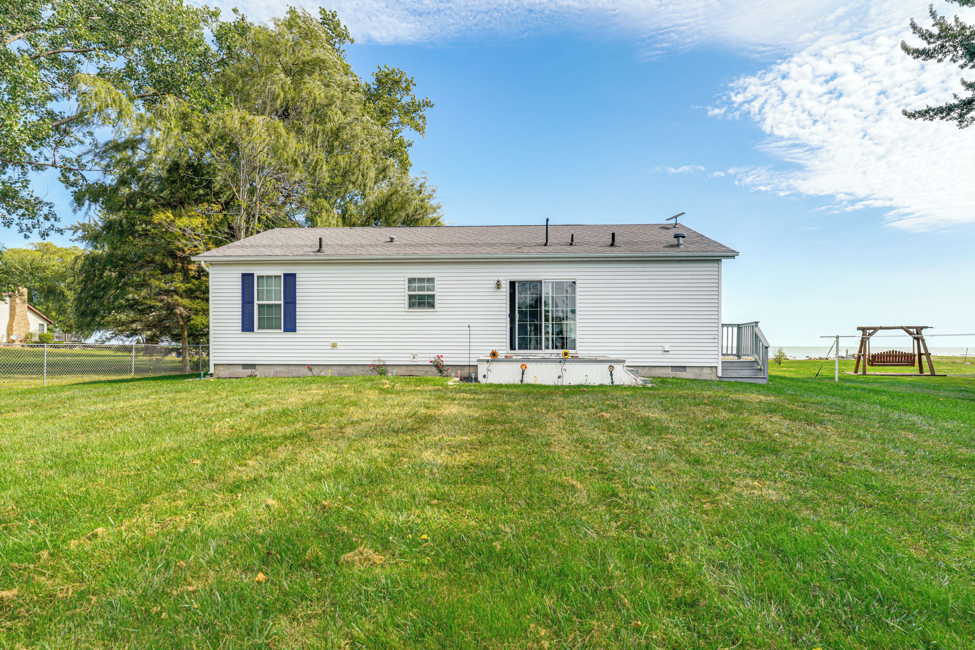 A single-story house with a front porch, a fenced yard, and a swing set.