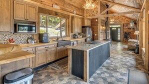 A spacious kitchen with wooden cabinets, a large island, and a stone-patterned floor. - Luxe Cabin Compound 4 Mi to Cameron State Forest! (Cameron)