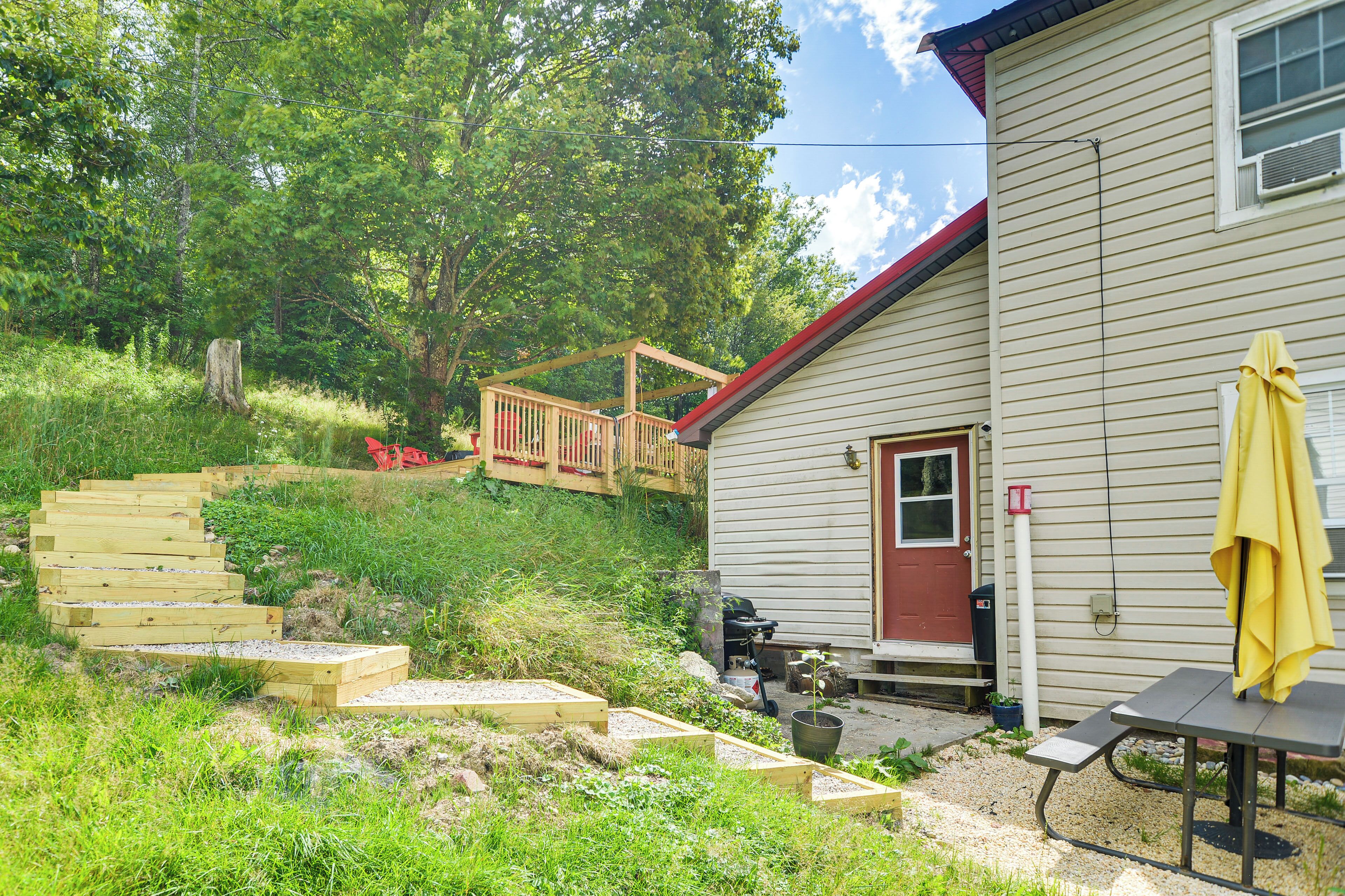 A residential property with a wooden deck, a red door, and a yellow umbrella.