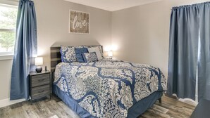 Un dormitorio con cama, mesita de noche y ventilador de techo.