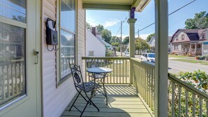 A porch with a table and chairs, a mailbox, and a view of the street and houses.