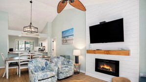 A living room with a fireplace, a television, and a dining area with a table and chairs. - 2D West Hyde Park - Your New Favorite Beach Villa (Myrtle Beach)