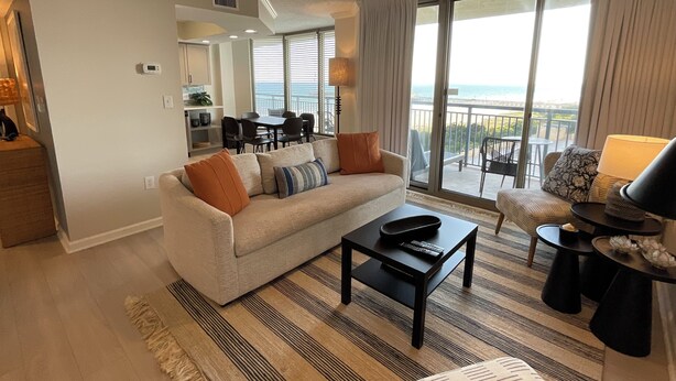 A modern living room with a sofa, coffee table, and a balcony with a view.
