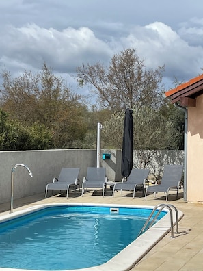 A swimming pool with lounge chairs and a faucet.