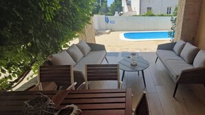A patio area with a pool, outdoor furniture, and a view of the surrounding buildings.